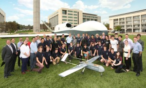 Chief of Air Force AIRMSHL Geoff Brown, Northrop Grumman Australia CEO Ian Irving, and students of Canberra's Dickson College pose in front of a full-scale mock-up of the company's MQ-4C Triton in Canberra. (Northrop Grumman)