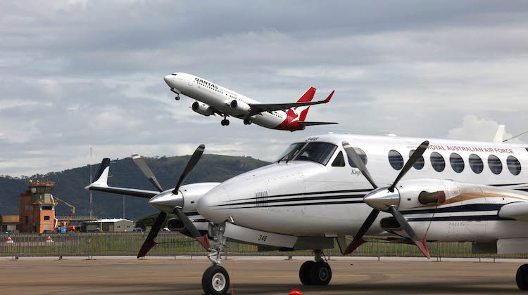 A Qantas aircraft takes off from Townsville Airport, with a 32 King Air K-350 Aircraft sits on the hardstand at RAAF Base Townsville. (Defence)