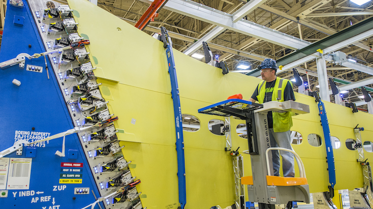 A Boeing Renton employee loads wing skin panels and stringers onto a 737 MAX wing. (Boeing)