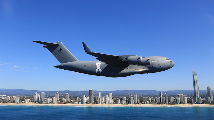 A C-17 with a white ribbon on the fuselage on its flypast. (Defence)