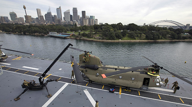 An Australian Army CH-47F Chinook helicopter has its rotors removed in order to be lowered into the hangar of HMAS Canberra.