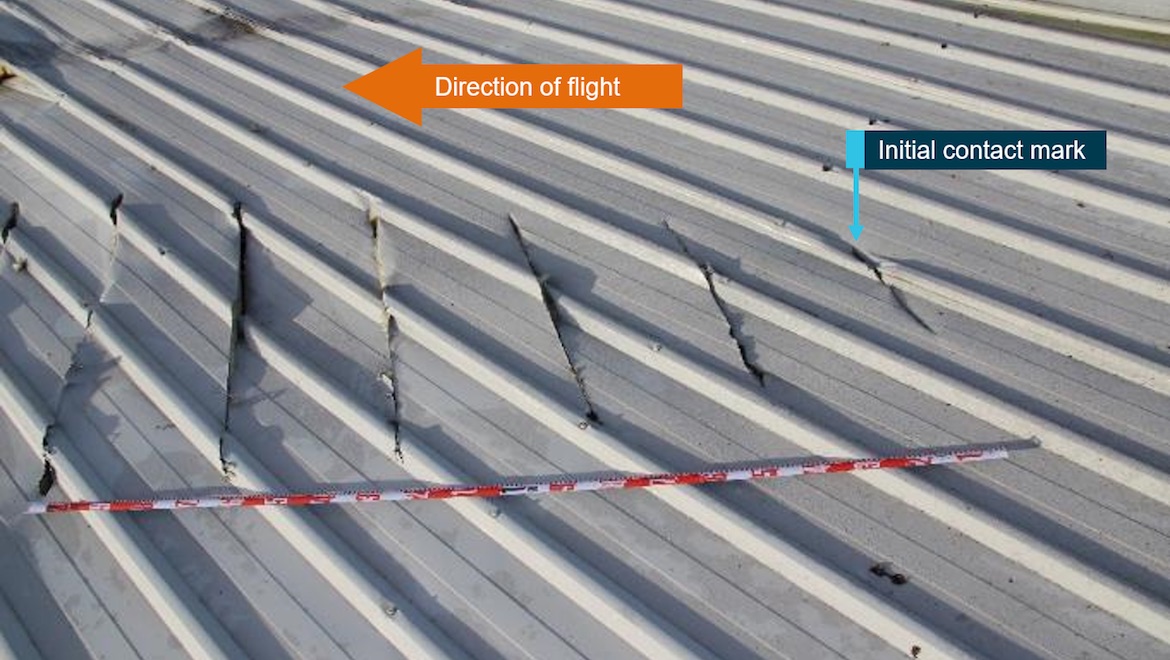 Left propeller slash marks in roofing material with tape measure showing distance between cuts. (ATSB)